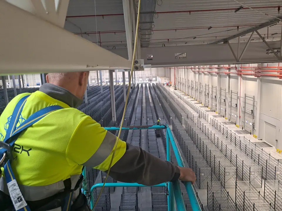 Prace instalacyjne na wysokości w rozległej hali przemysłowej
